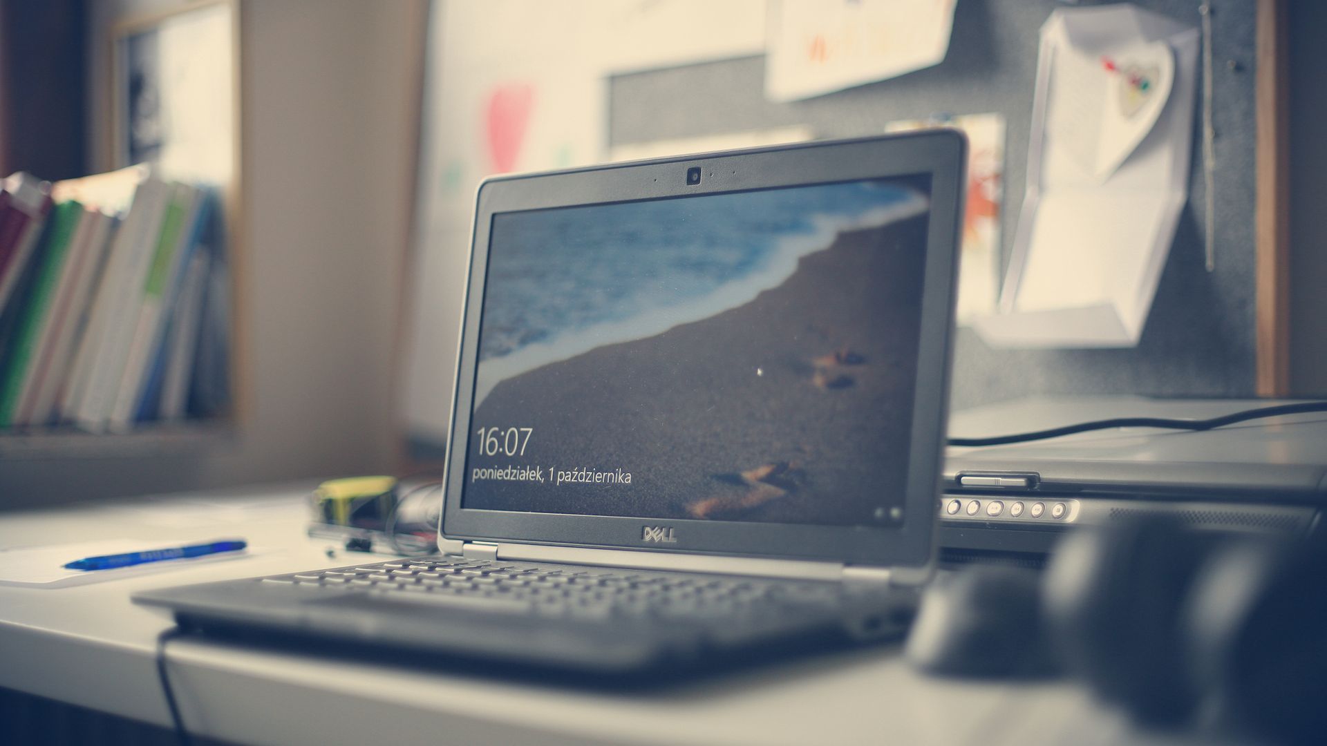 Dell-Notebook an einem Schreibtisch mit Büchern und Schreibutensilien; Symbolbild für Computer im Büro.
